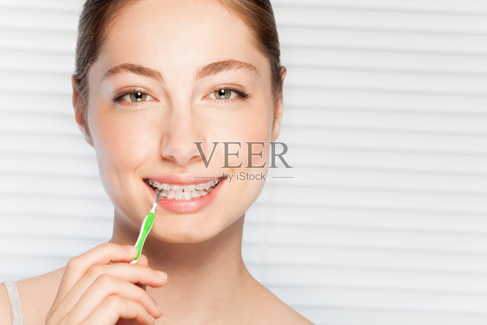快乐的女人用牙间刷清洁牙箍照片摄影图片