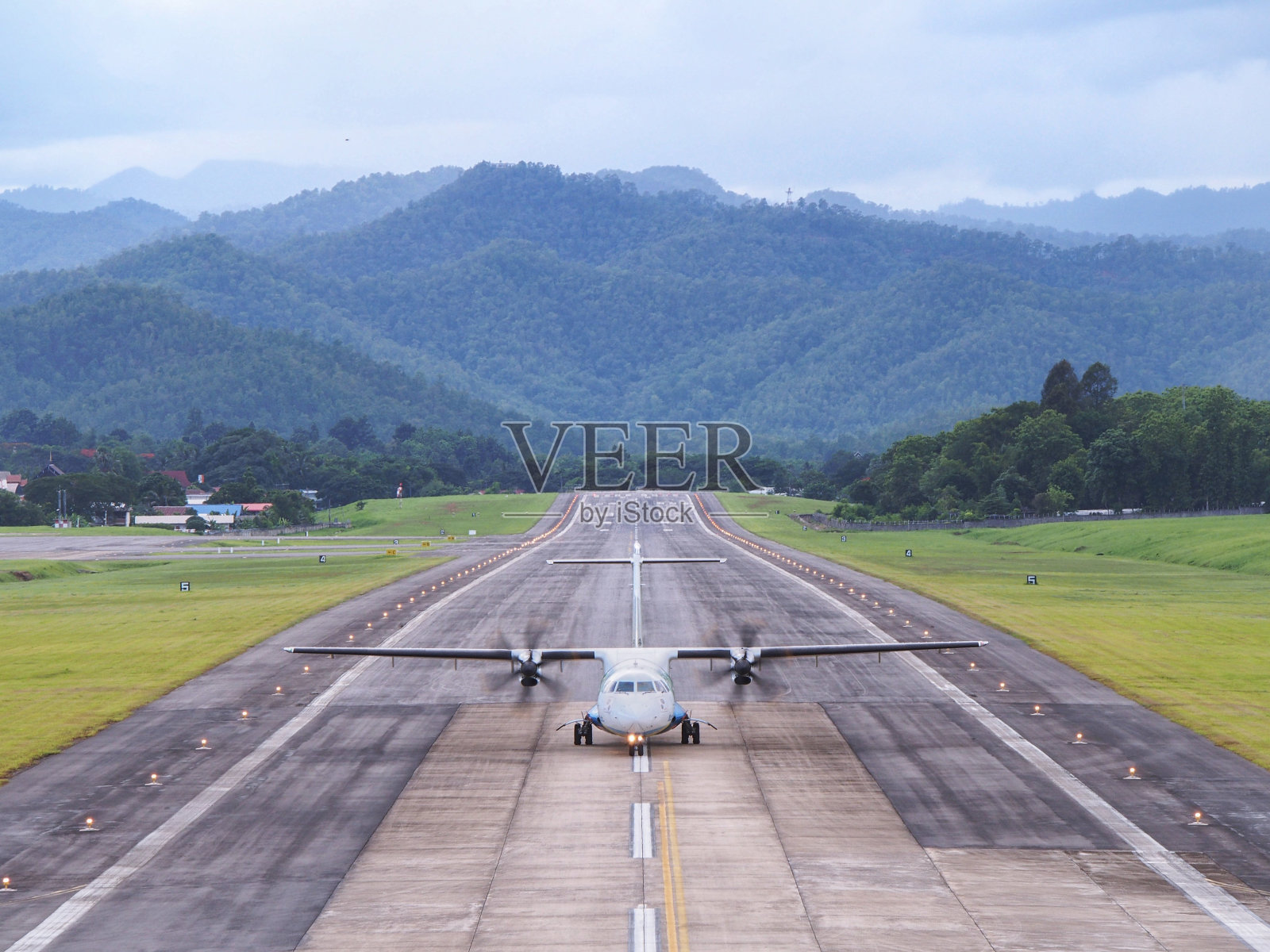 在群山环绕的机场跑道上，飞机正在滑行、降落或起飞。照片摄影图片