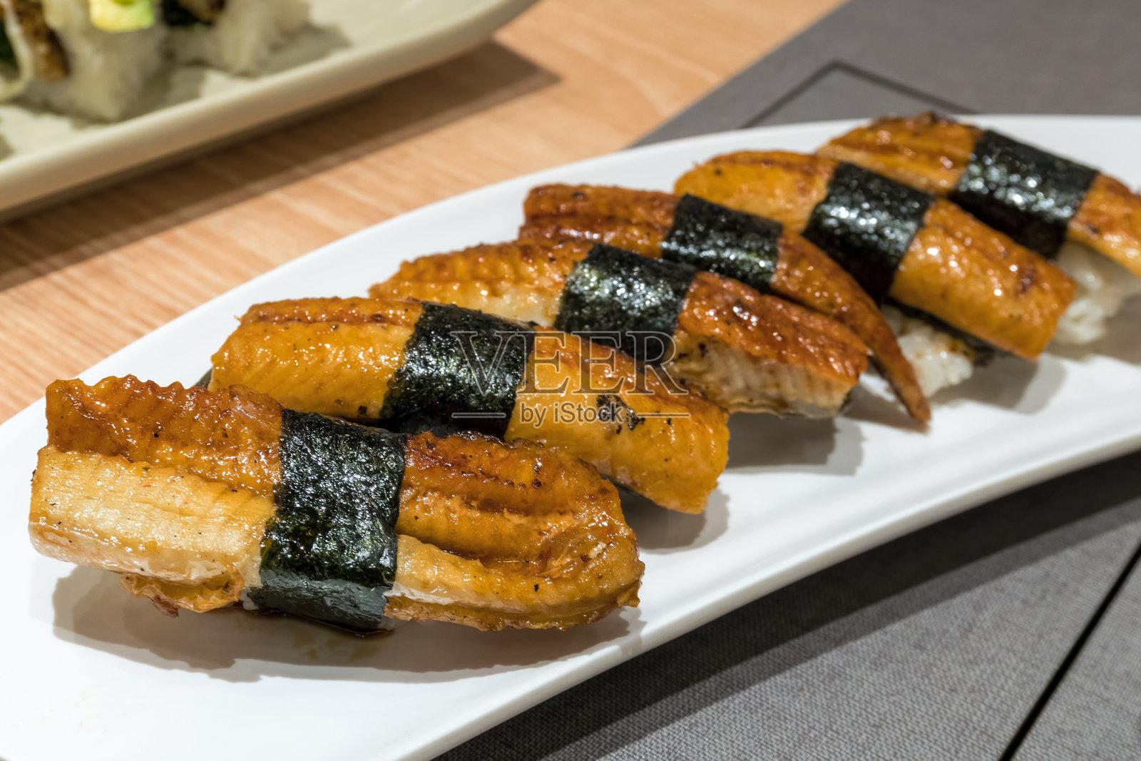 鳗鱼寿司包米饭和海藻在白色陶瓷盘子上特写照片摄影图片