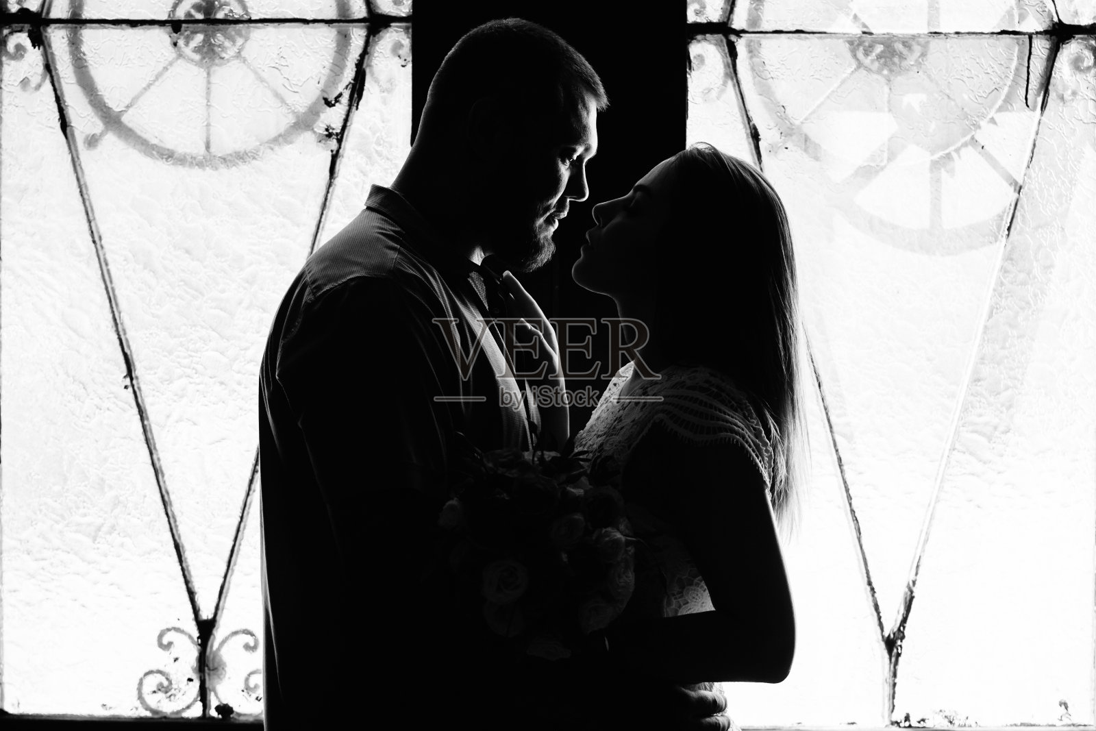 一对浪漫的夫妇在一个背光从窗户或门，一对夫妇的剪影在门口用背光，一对情侣新郎和新娘在窗口，黑白摄影照片摄影图片