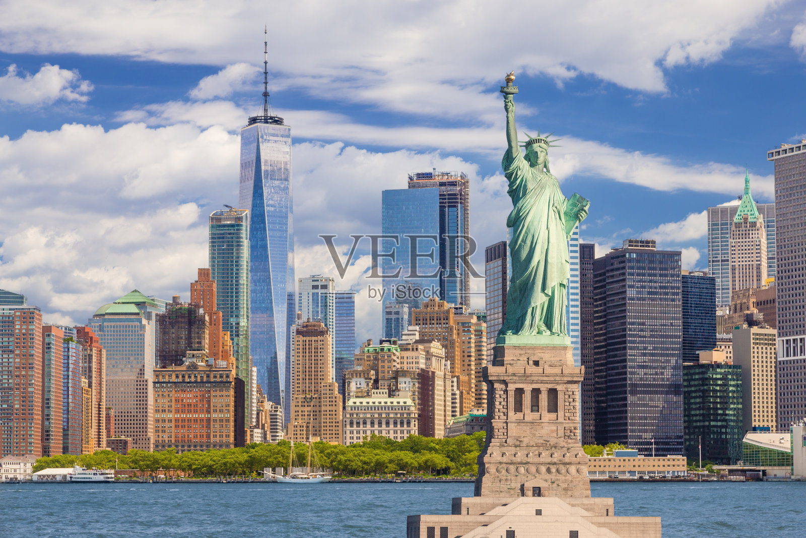 自由女神像和纽约天际线，曼哈顿金融区，世界贸易中心，纽约港水，炮台公园和蓝天。照片摄影图片