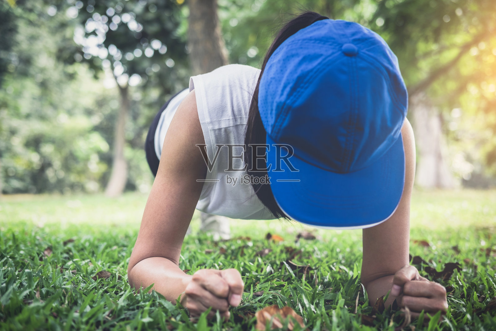 年轻女子在夏天公园的草地上做平板支撑照片摄影图片