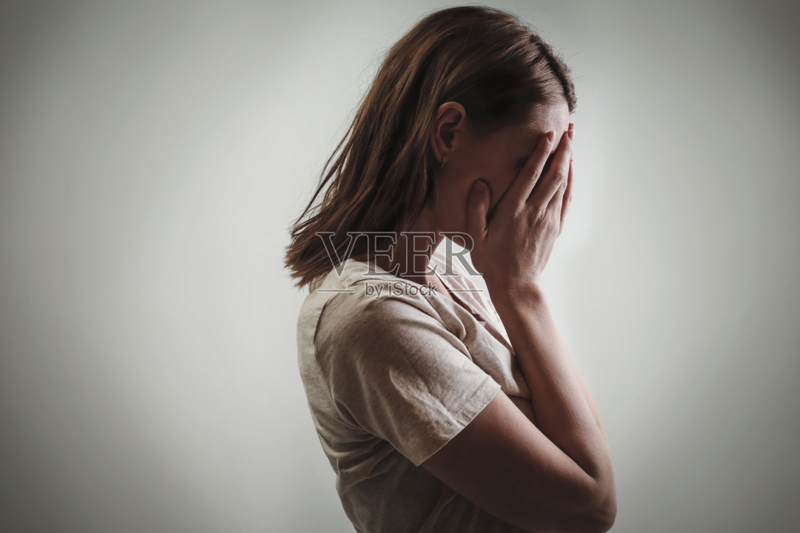 一个沮丧的女人的肖像，用她的手遮住脸，侧视图照片摄影图片