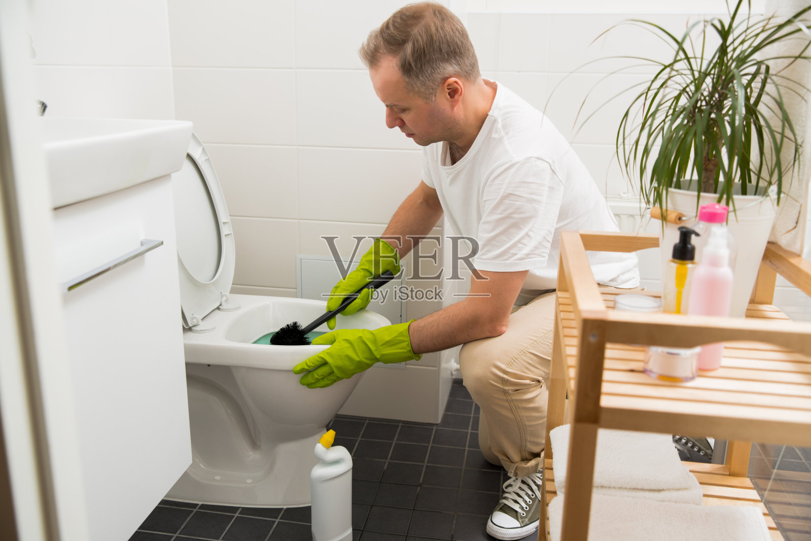 戴着橡胶防护手套的人用刷子和清洁剂清洗厕所照片摄影图片