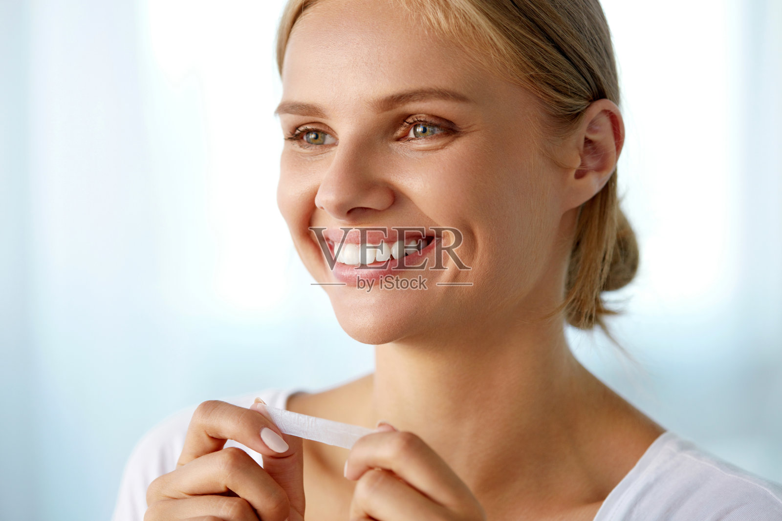 女人使用牙齿美白带美丽的白色微笑照片摄影图片