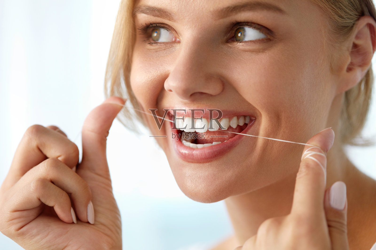 牙齿保健。美丽微笑的女人用牙线清洁健康洁白的牙齿照片摄影图片