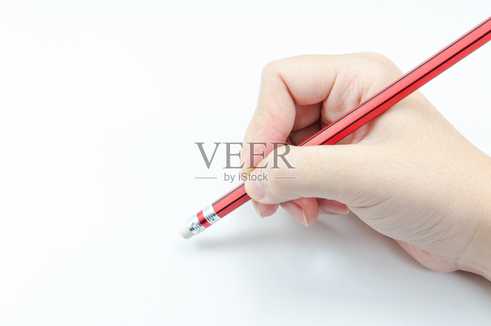女人的手拿着红色的铅笔在白色的橡皮擦上照片摄影图片