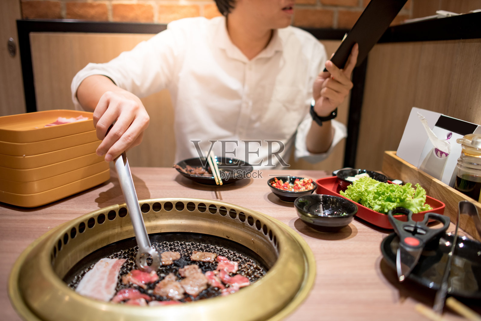 年轻的亚洲男子在餐厅吃韩国烧烤自助餐照片摄影图片