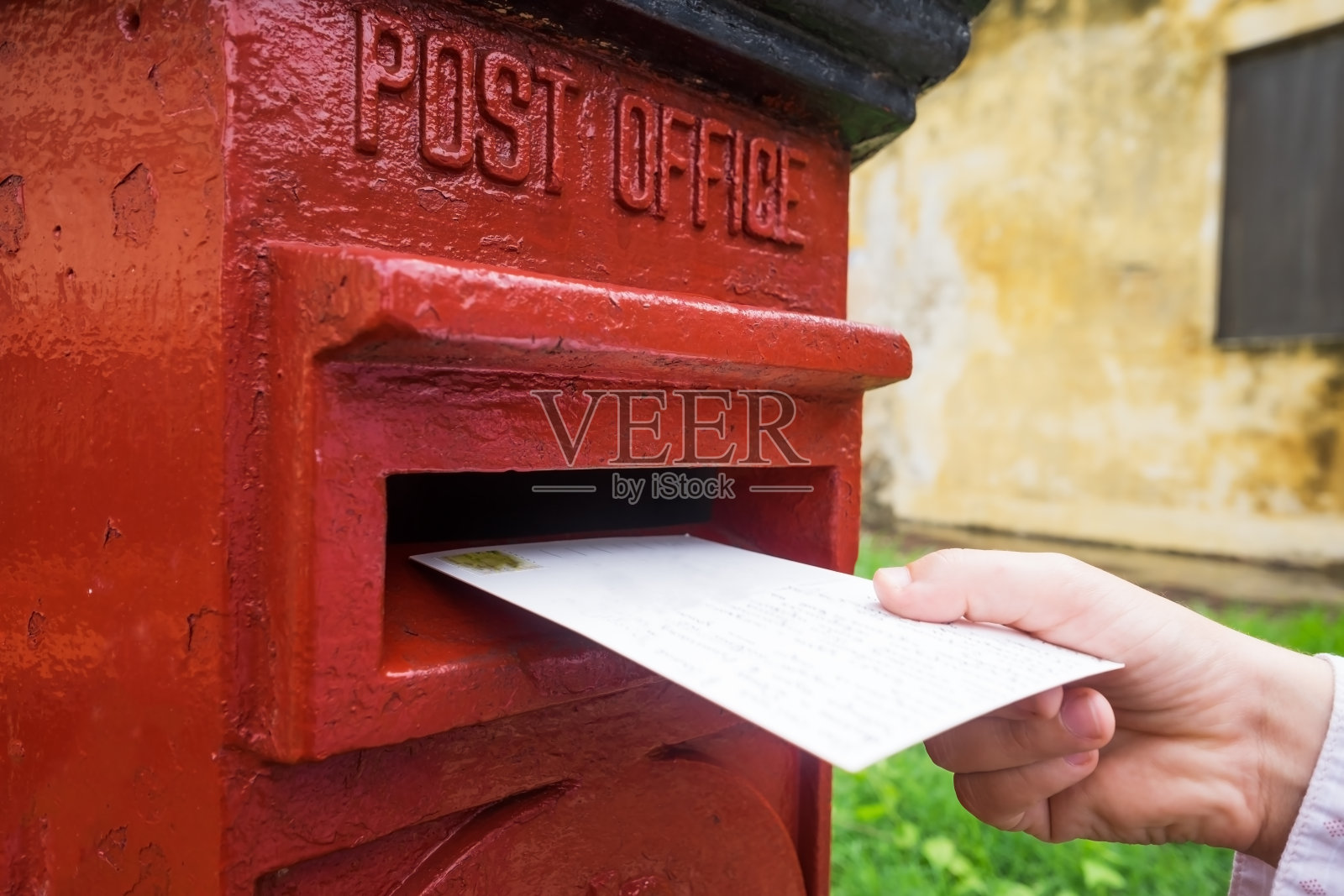特写是一个男人正在把一封信放进一个红色的信箱里。复古式交流的概念。照片摄影图片