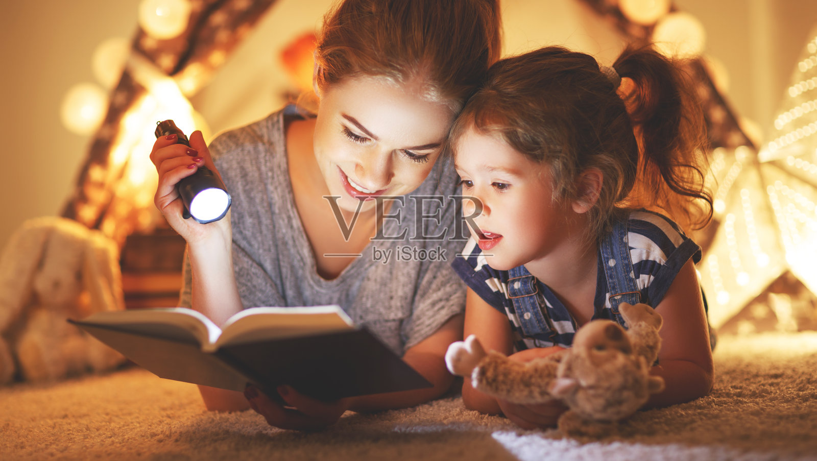 妈妈和孩子在睡觉前看一本书和一个手电筒照片摄影图片