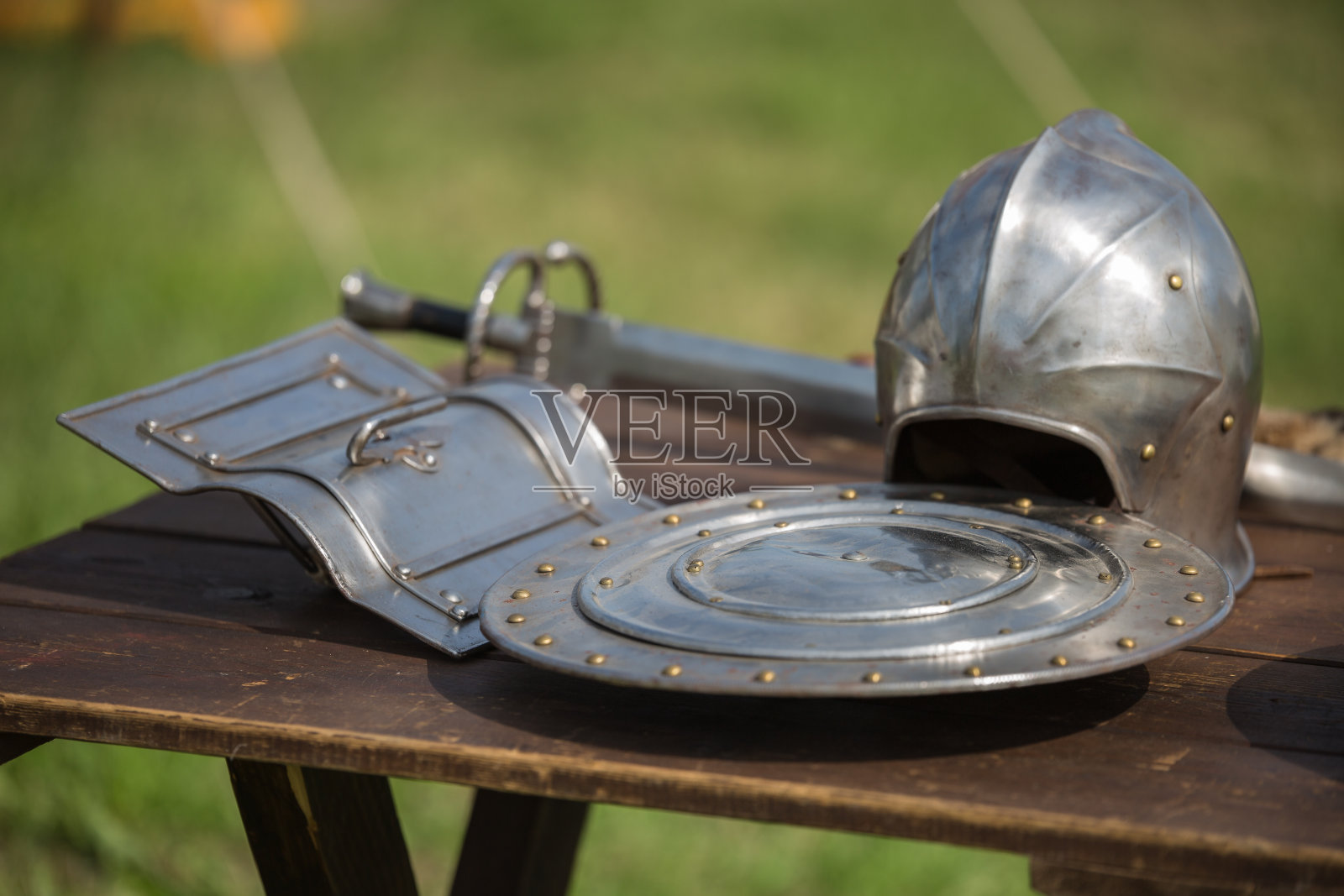 头盔，盾牌和中世纪金属盔甲和武器，户外木制桌子照片摄影图片