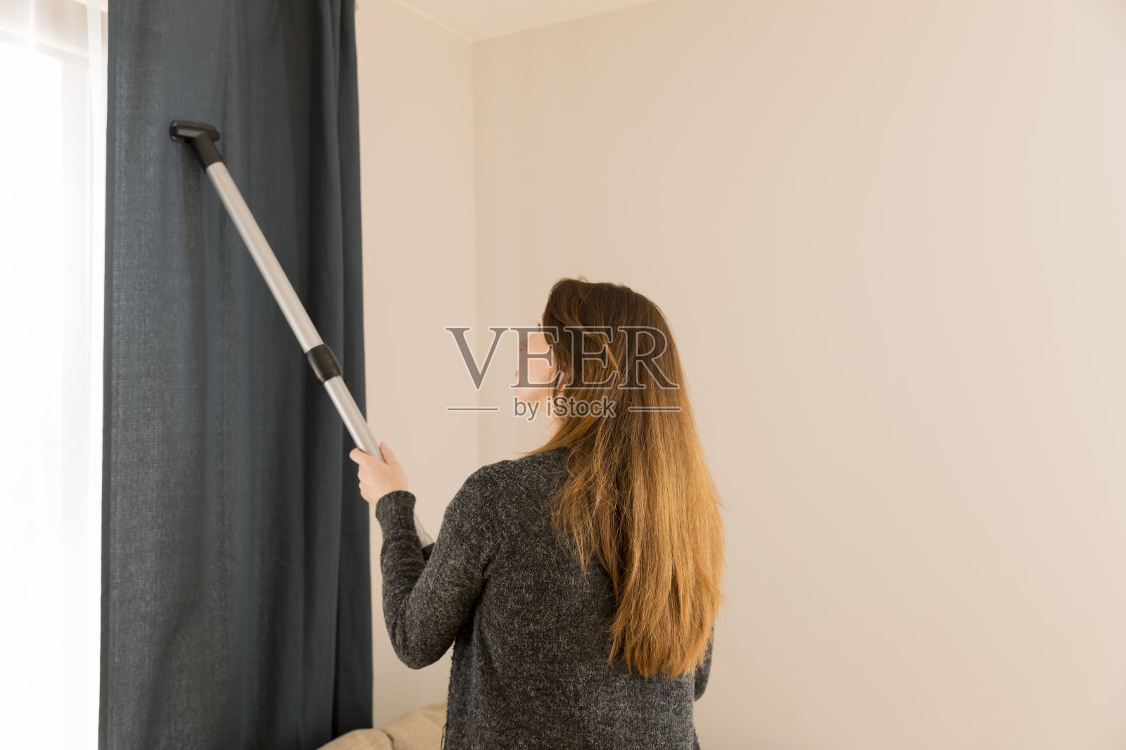 人，家务和家政概念-妇女与吸尘器在家。窗帘清洗。春季大扫除照片摄影图片