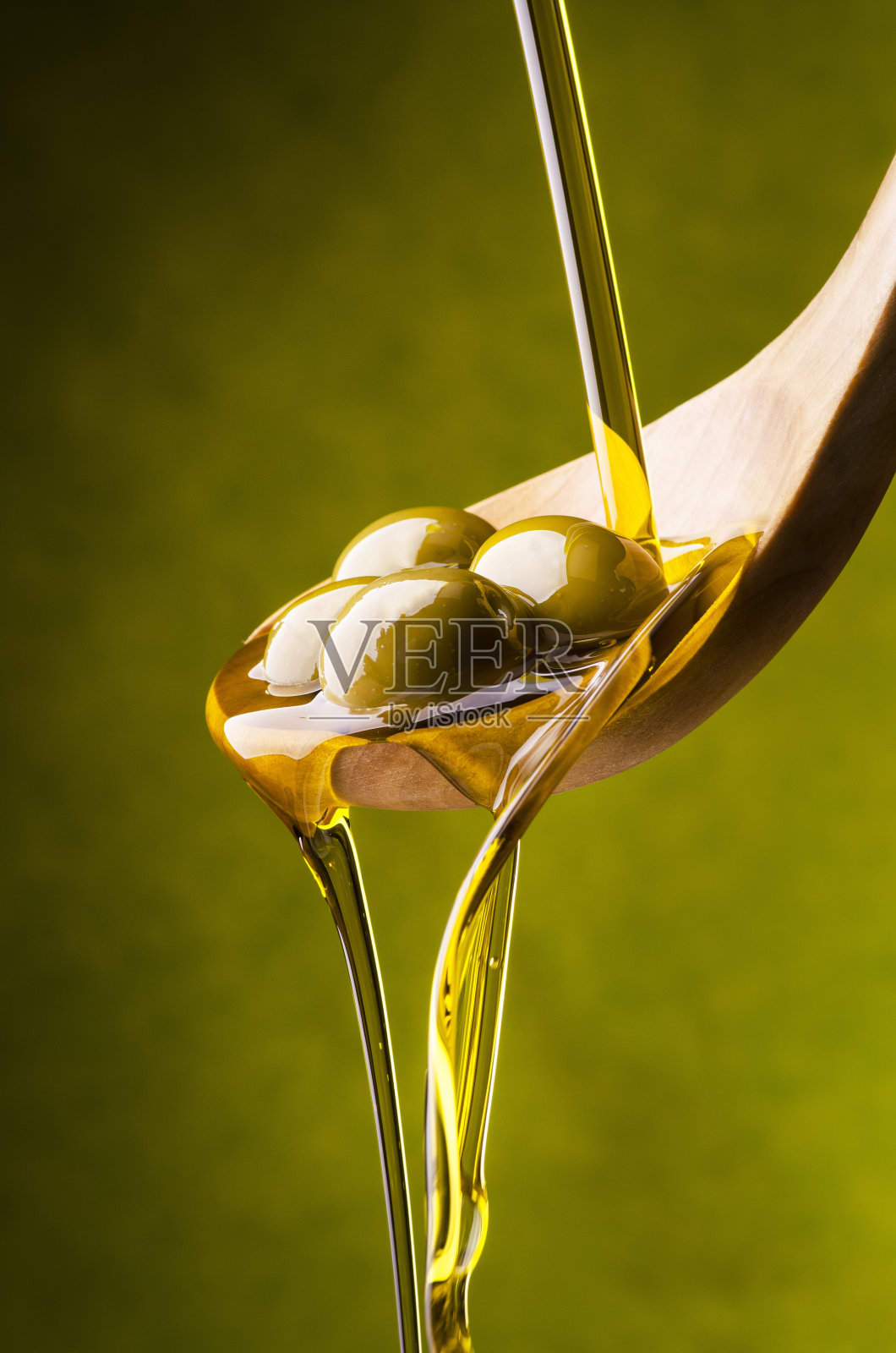 橄榄油落在木勺里的绿橄榄上照片摄影图片