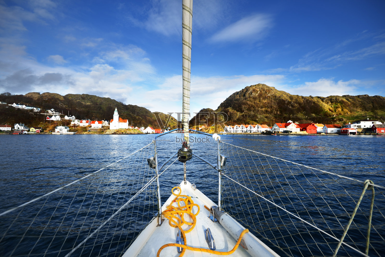 从峡湾里的一个挪威小村庄的游艇船头观看照片摄影图片
