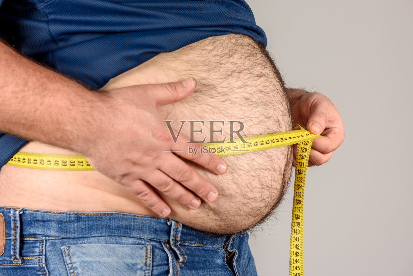 超重，毛人用卷尺测量他的肚子照片摄影图片