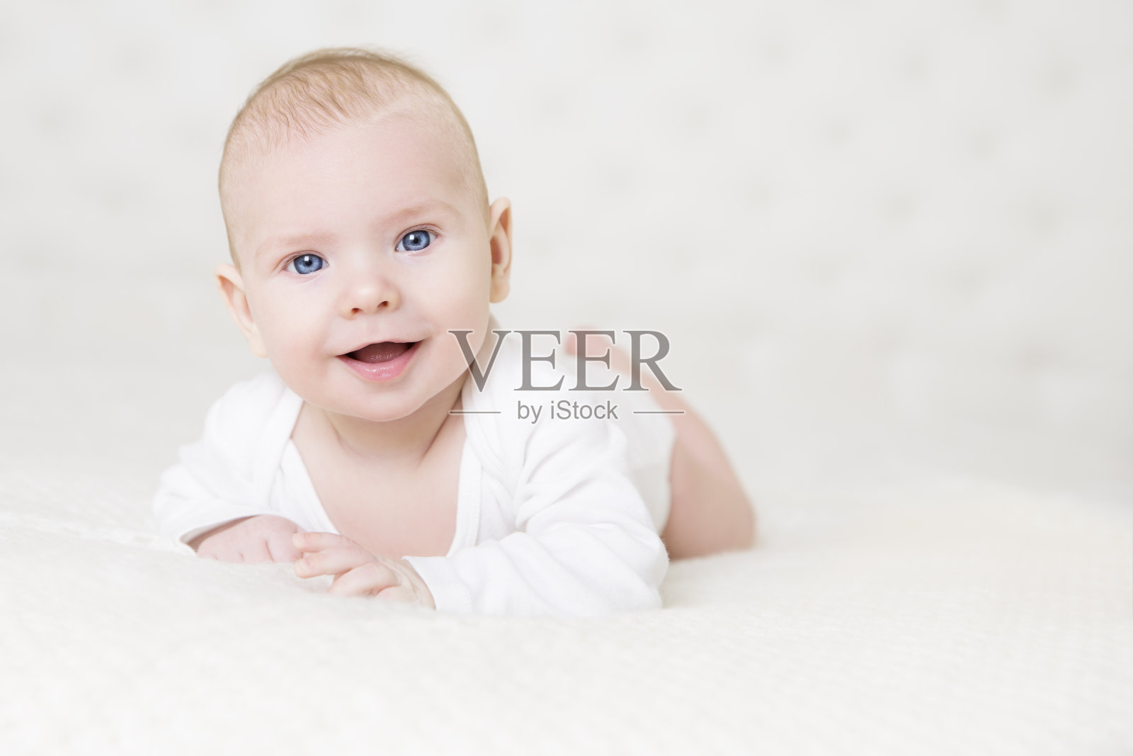 婴儿在白色地毯上爬行，快乐的小男孩画像，微笑的婴儿男孩照片摄影图片