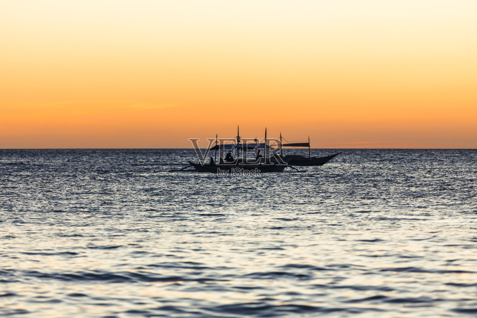 日落时地平线上的一艘支腿帆船照片摄影图片