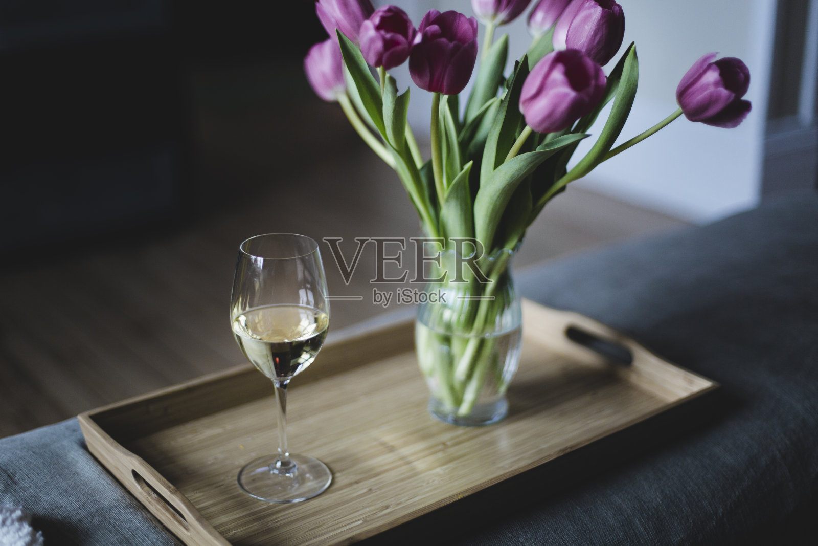 托盘上放着一束郁金香花和一杯葡萄酒照片摄影图片