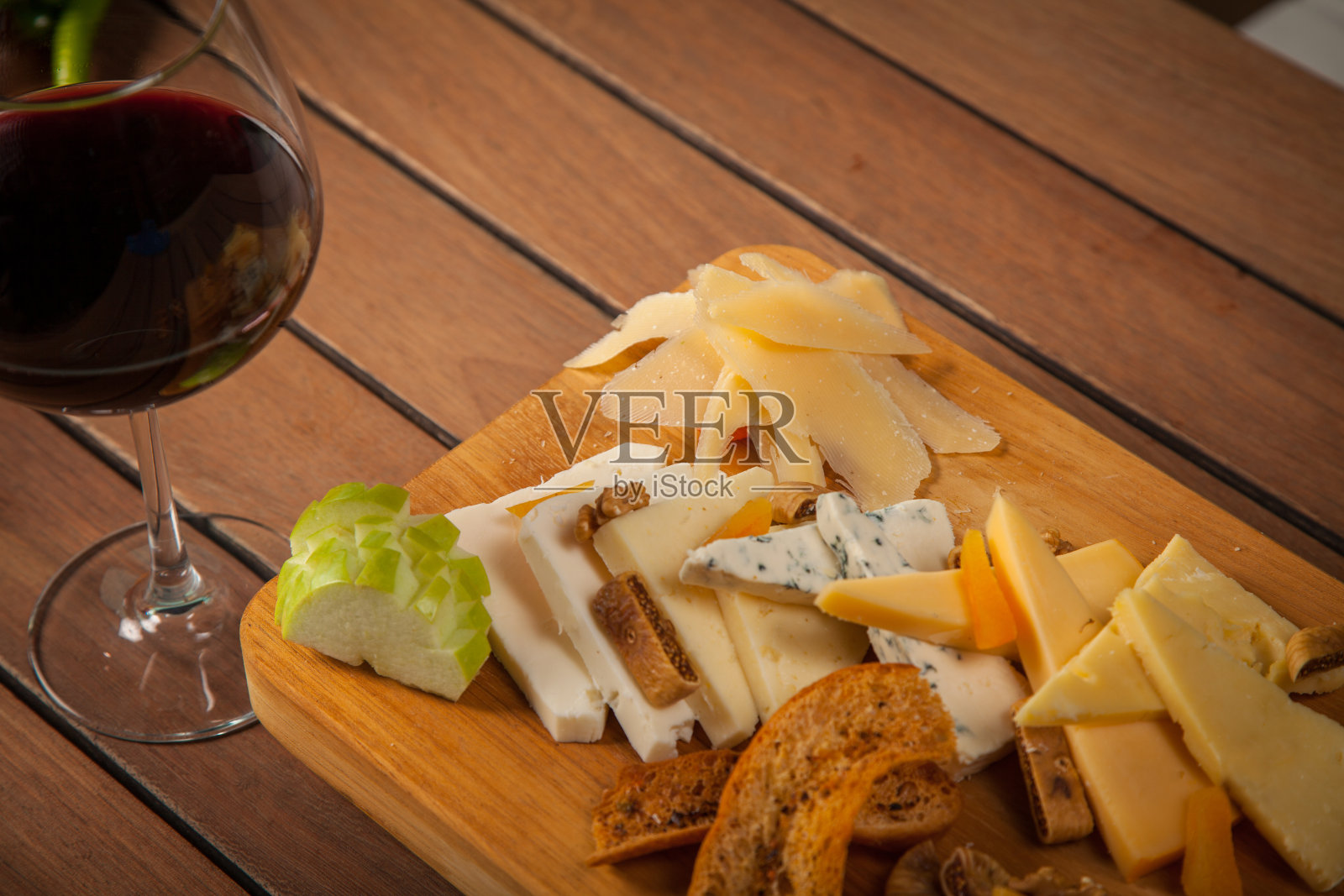 木制大浅盘上的什锦奶酪和红酒照片摄影图片