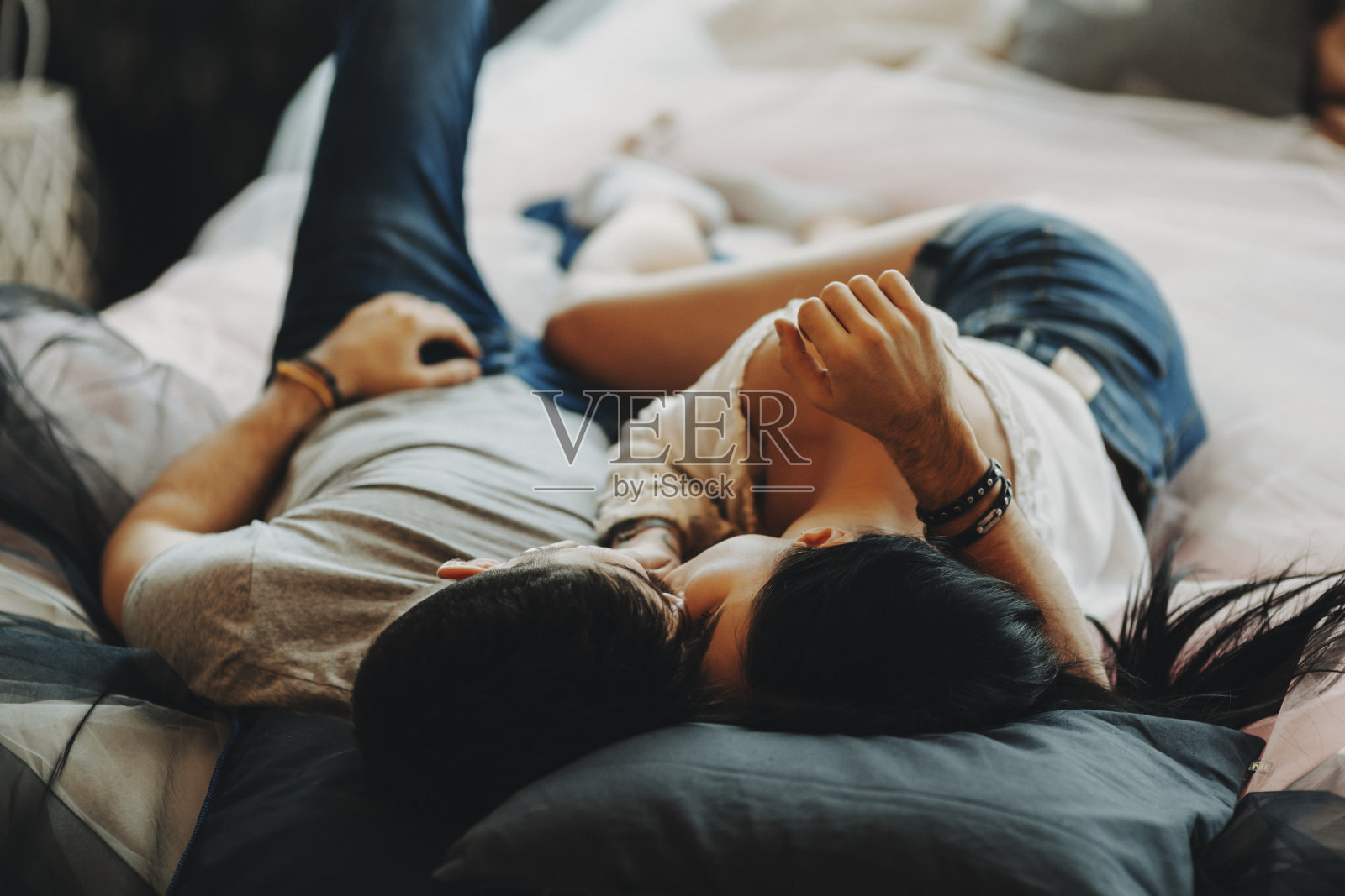 一对迷人的浪漫情侣躺在舒适的房间里拥抱亲吻。照片摄影图片