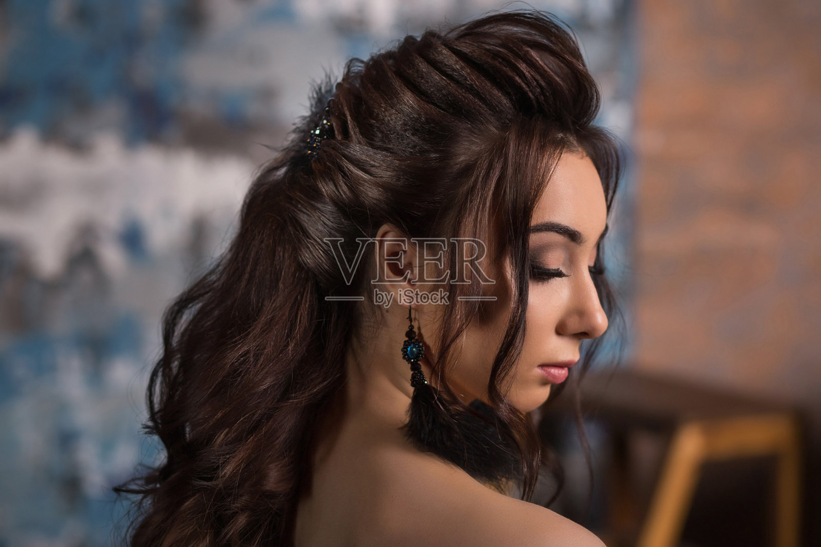 黑色的头发的女人。美丽的黑发发型时尚肖像与美丽的长羽毛耳环和黑色头发在黑暗的工作室背景照片摄影图片