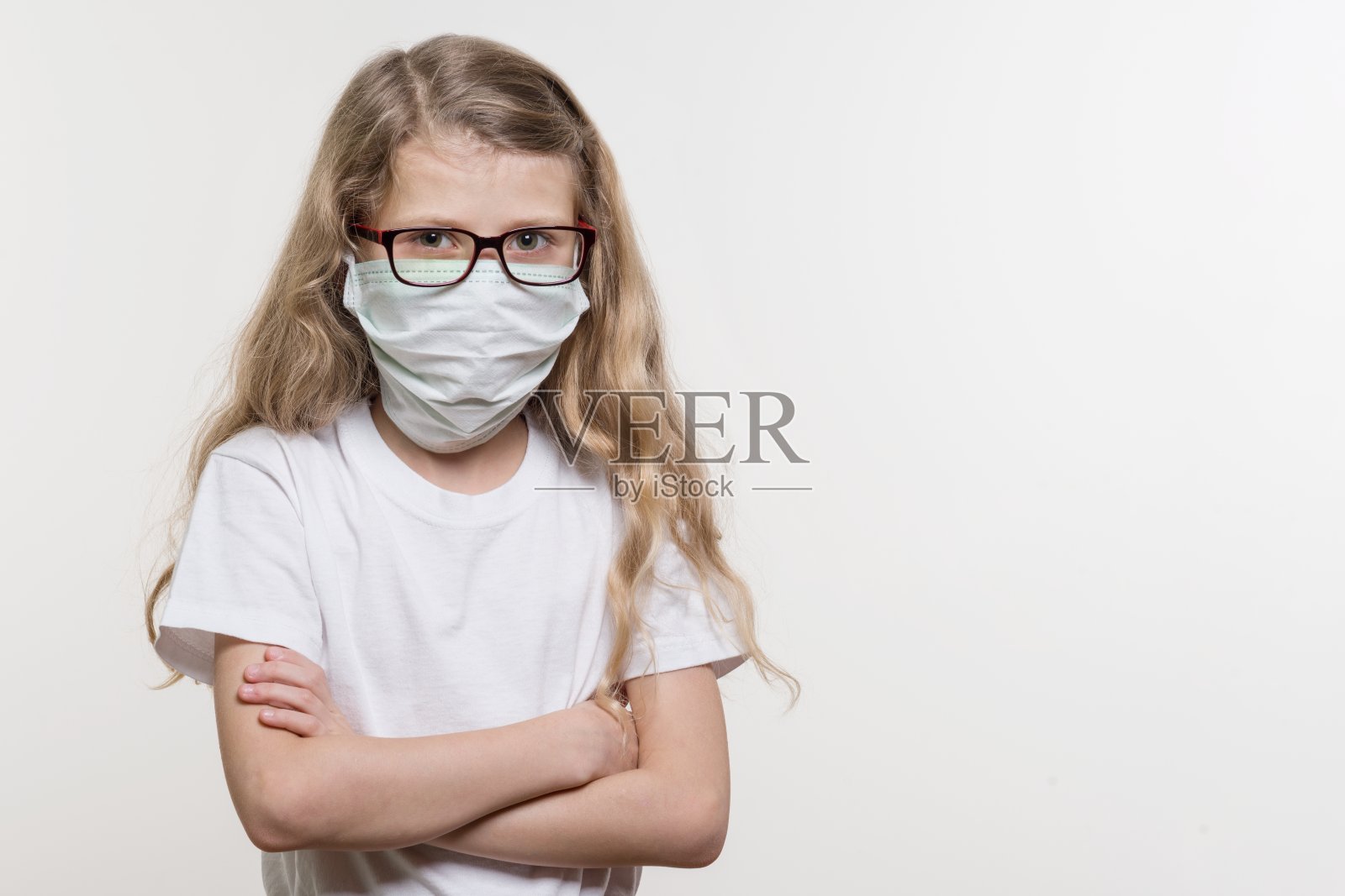 戴医用口罩的女童在一个白色的背景，在一个白色的基础t恤，复制空间。照片摄影图片