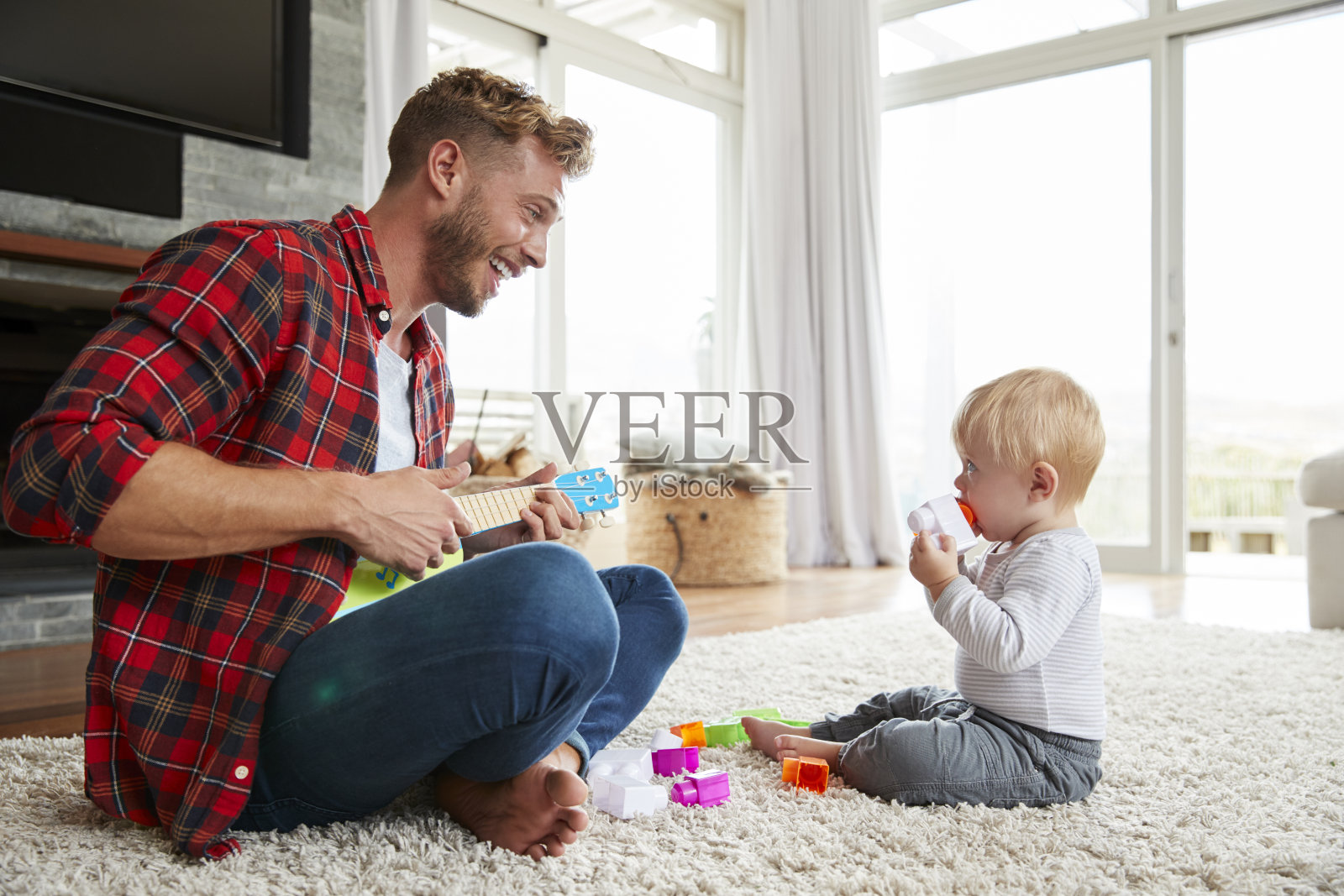 父亲和小儿子在家里弹奏四弦琴，特写照片摄影图片