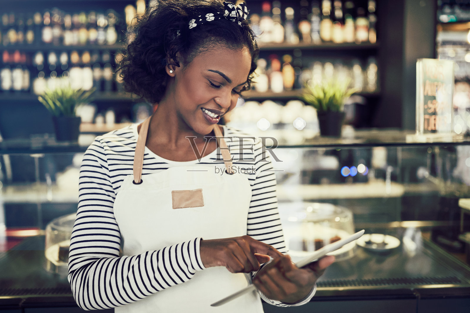 年轻的非洲企业家站在她的咖啡馆里用着平板电脑照片摄影图片