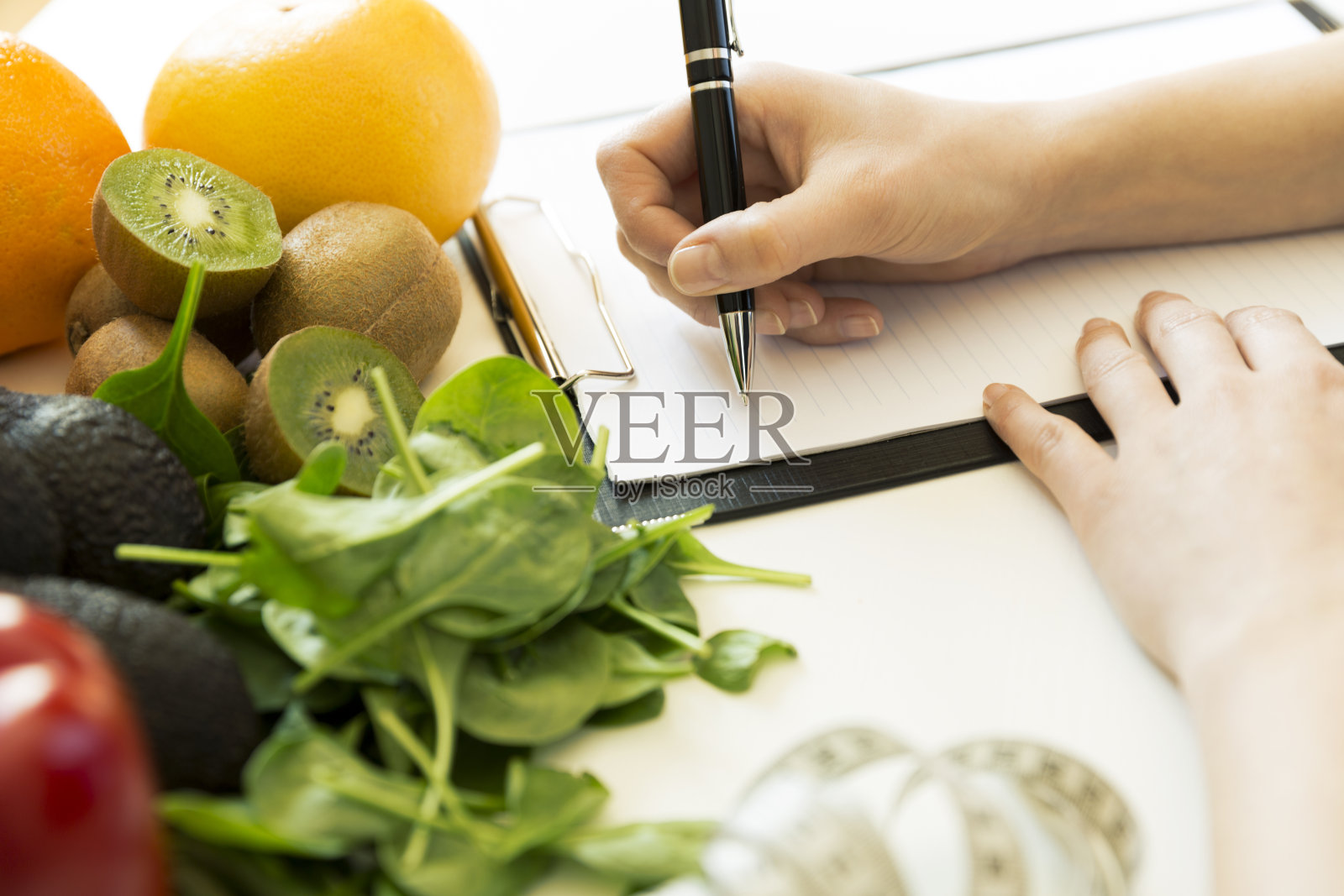 营养学家在桌子上写满了水果和蔬菜的饮食计划照片摄影图片