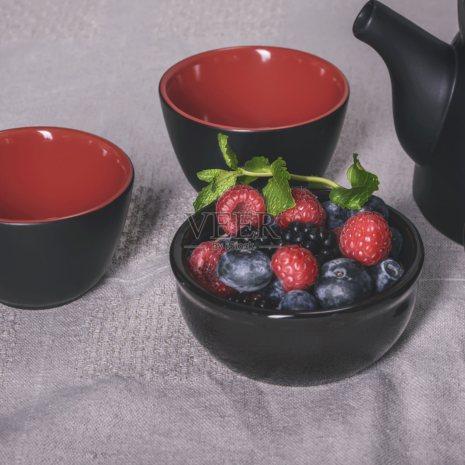 茶具摆放在桌子上，黑色和红色的杯子，上面有黑红色的浆果照片摄影图片