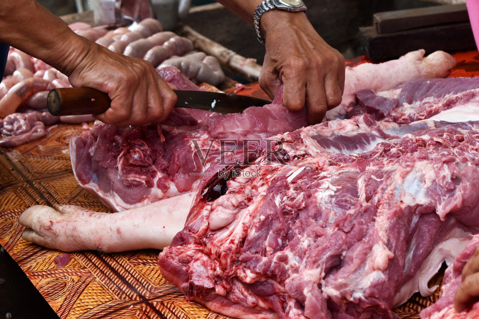 用刀切猪肉，准备为聚会做饭。照片摄影图片