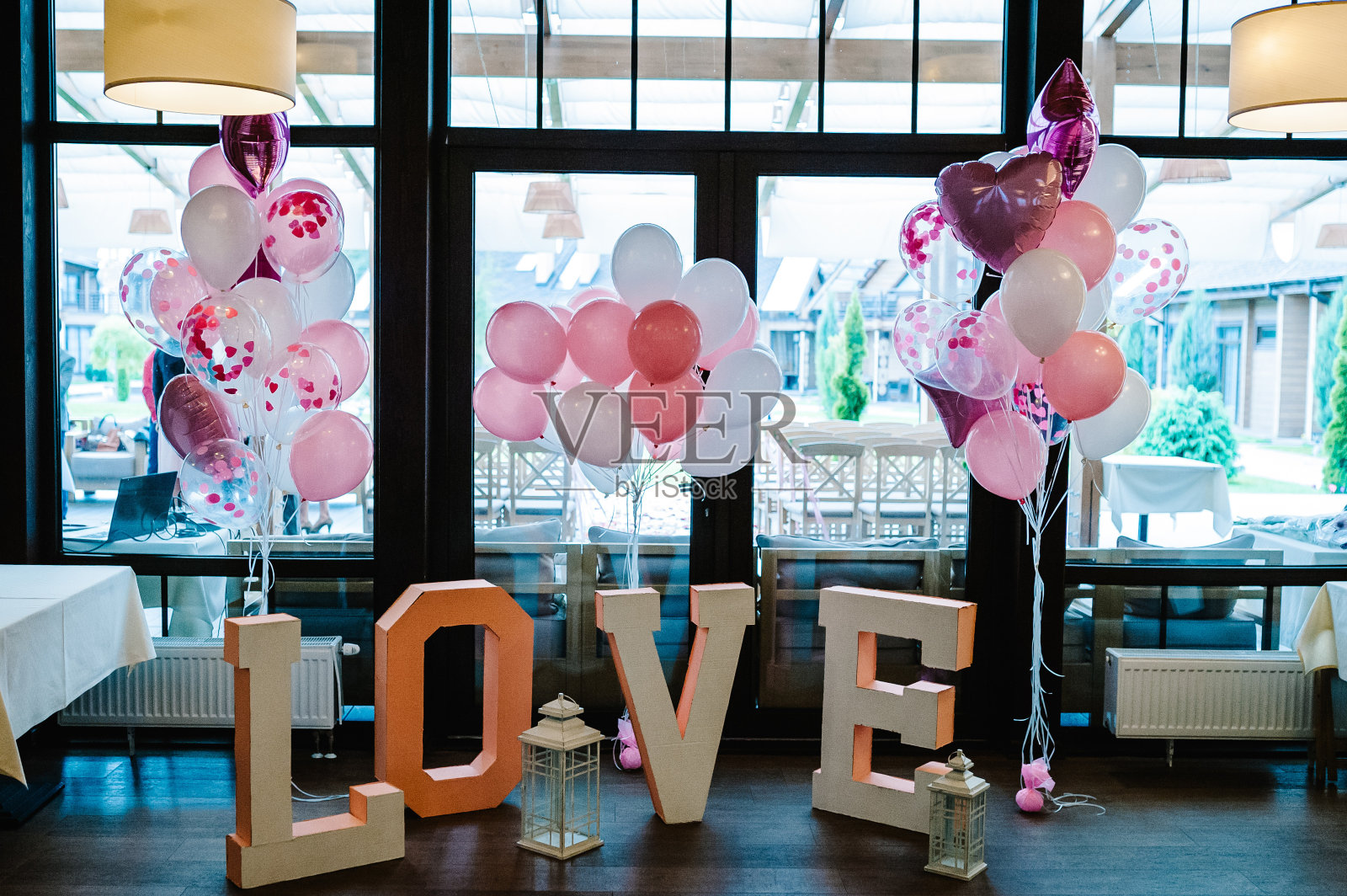 为了举行婚礼，当地一家餐厅的木地板上放着装饰好的大大的“爱”字和充气的粉色和白色氦气球。情人节和情人节照片专区。照片摄影图片