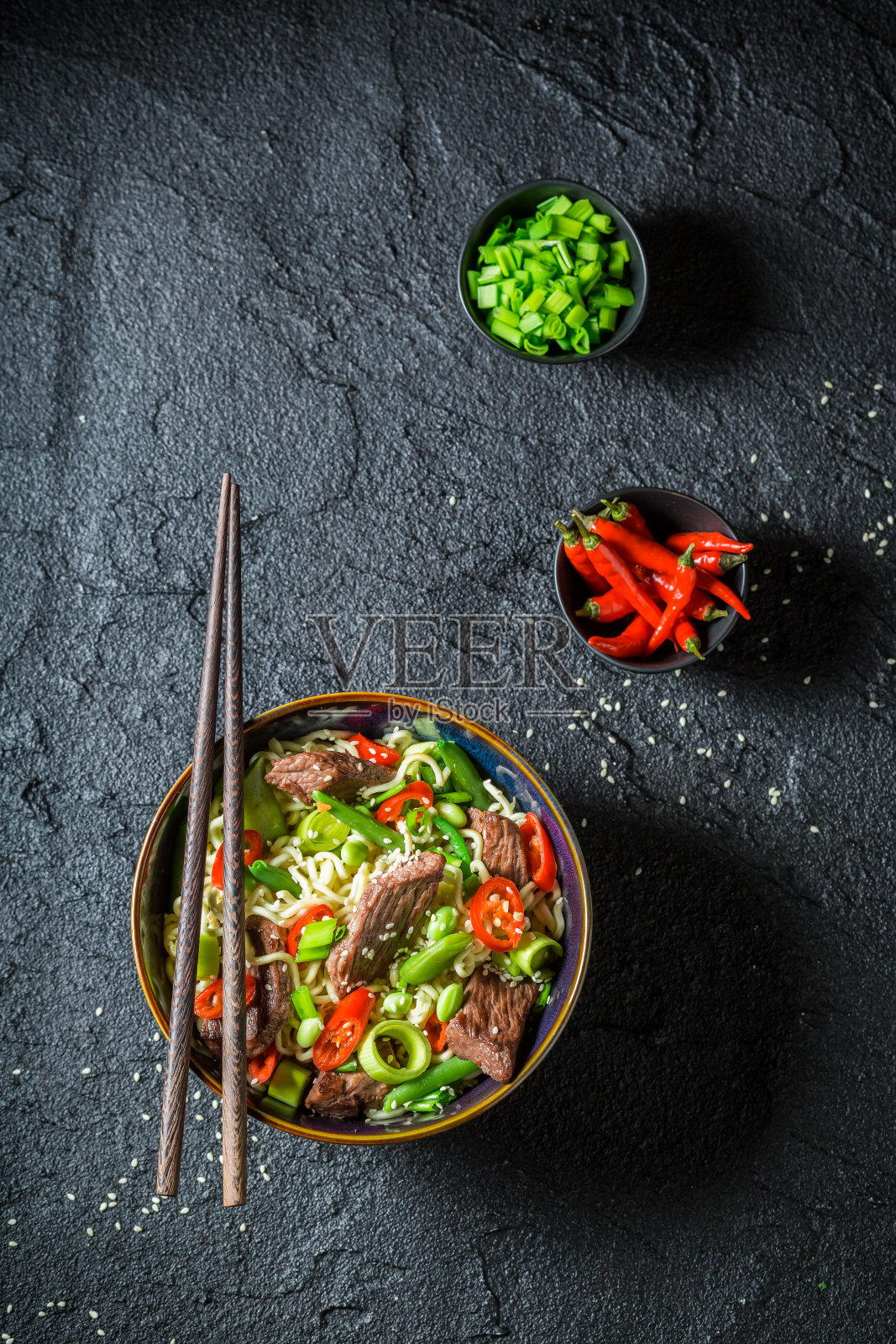 辣的亚洲面条和牛肉辣椒在黑色的桌子上照片摄影图片