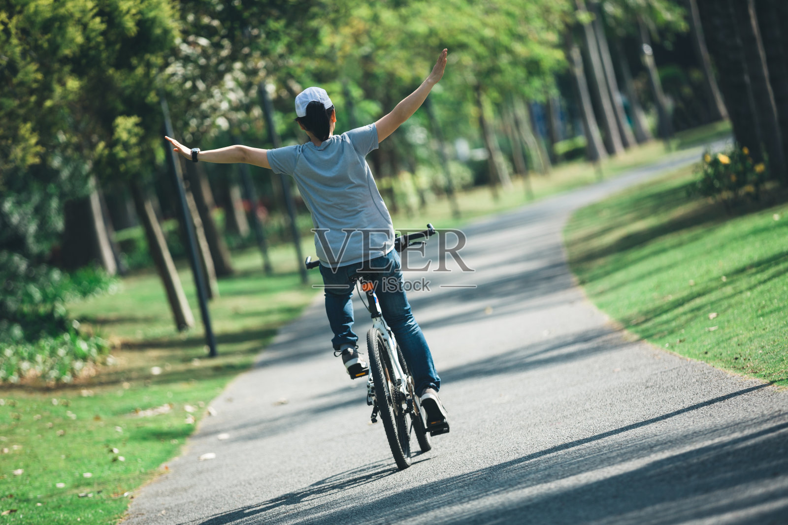 快乐的骑自行车的女人在热带公园骑自行车照片摄影图片