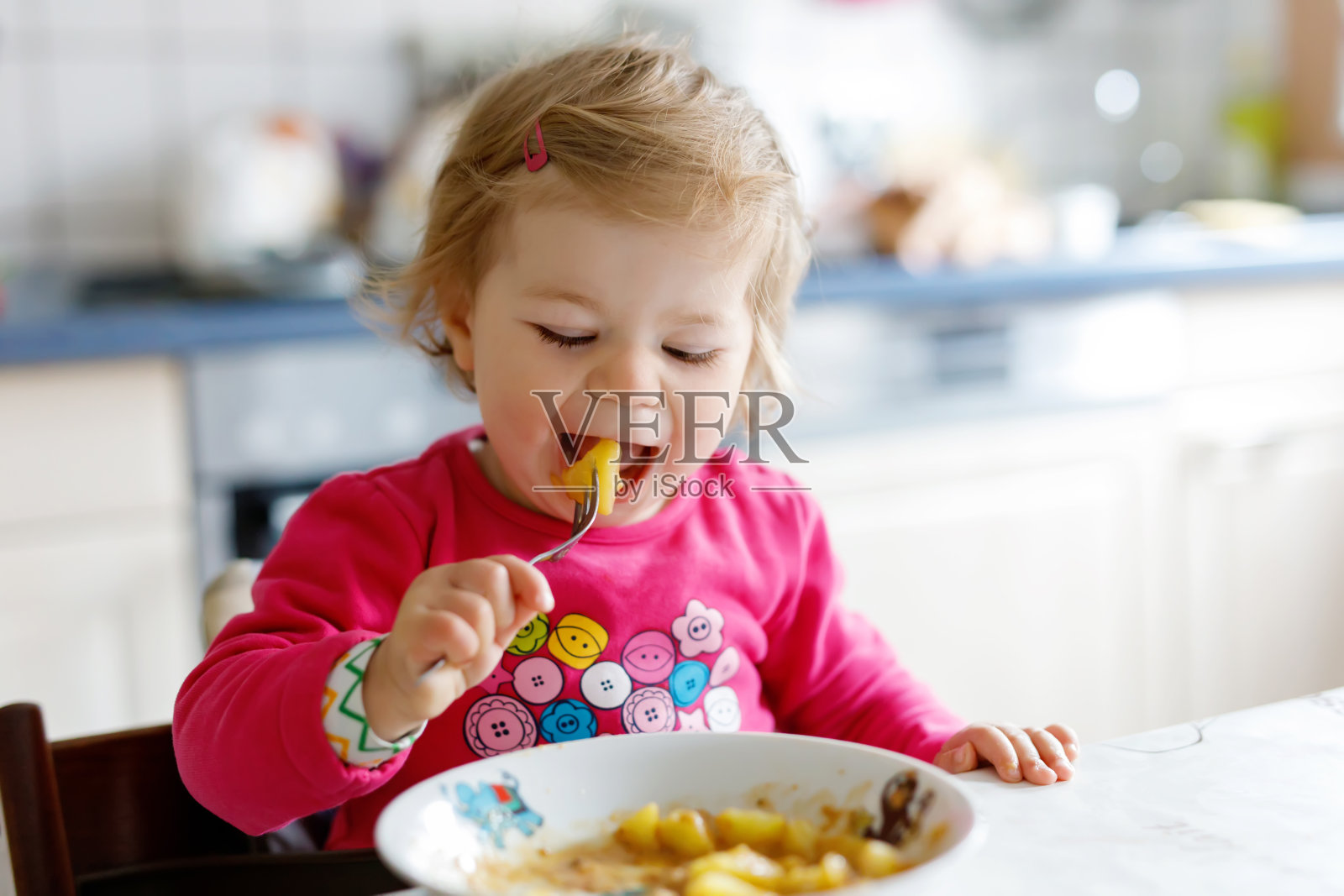 可爱的小女孩用叉子吃蔬菜和意大利面。食品、儿童、喂养和发展的概念照片摄影图片