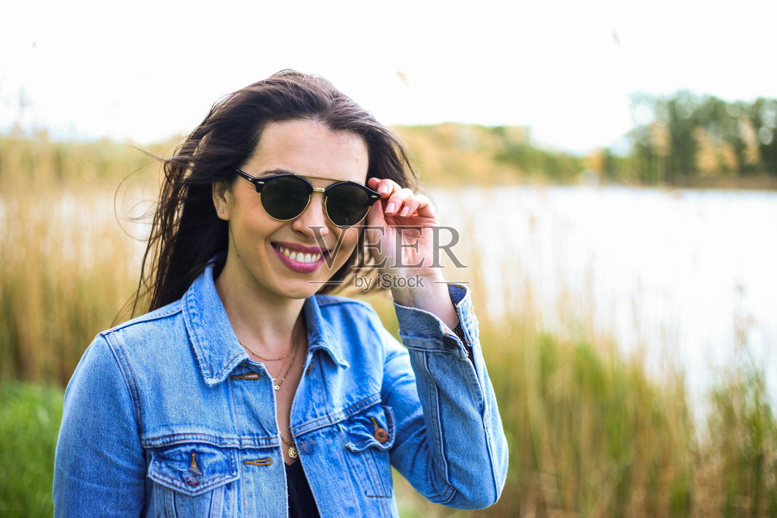 湖上有个穿着夹克戴着墨镜的女人照片摄影图片