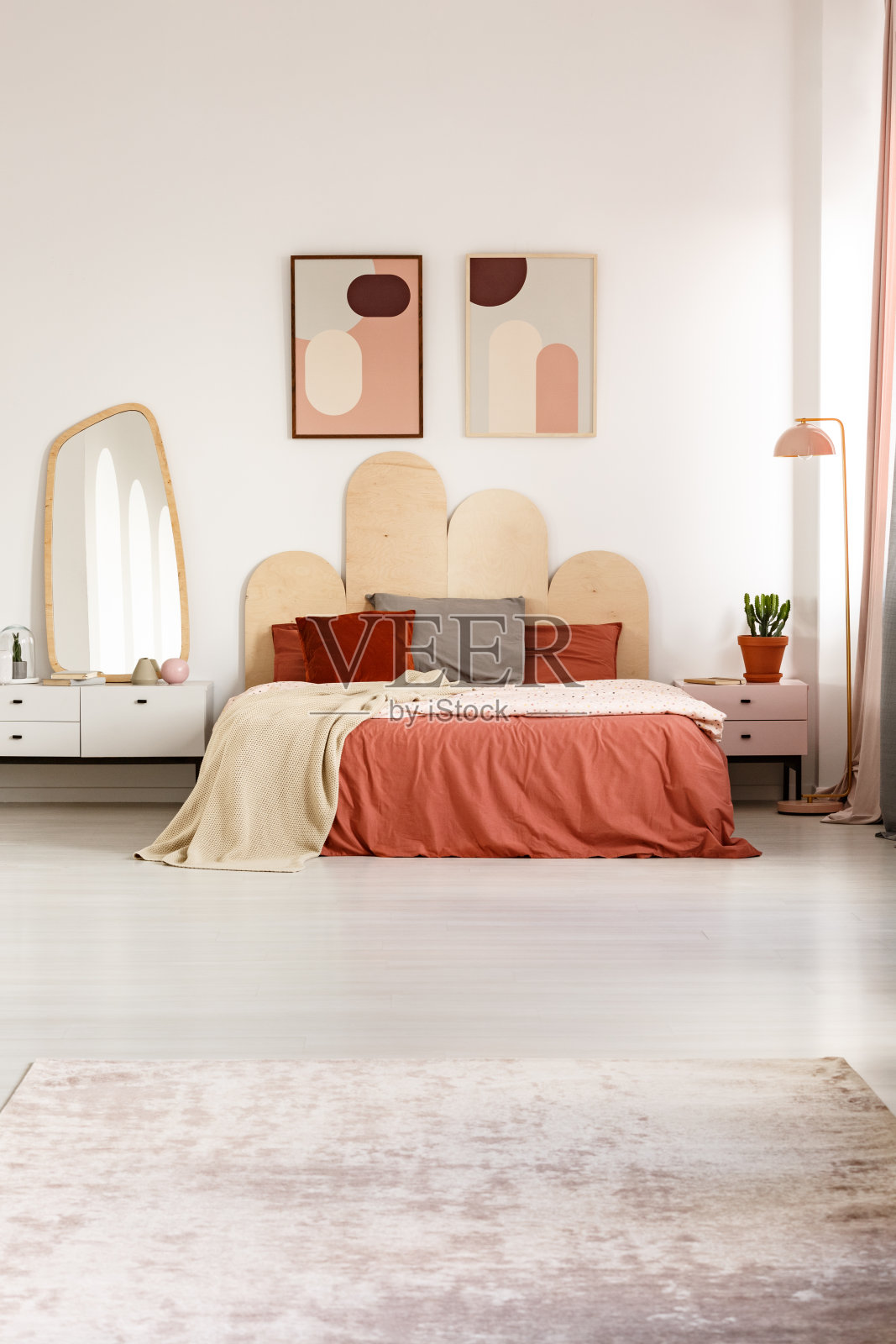 在现代卧室的室内，床上的红色床单，海报和镜子在橱柜上。真实的照片照片摄影图片