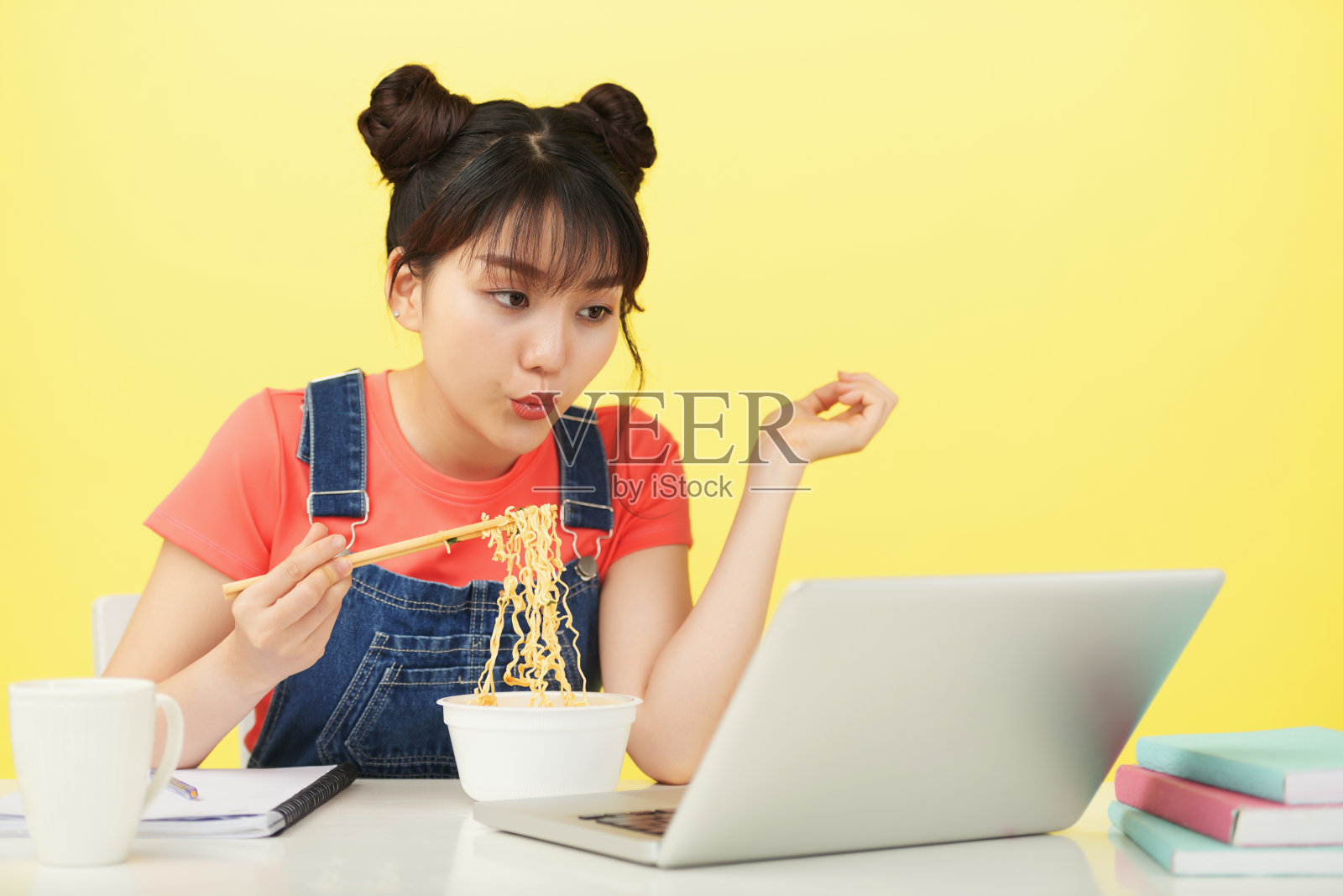亚洲女人一边吃面条一边看笔记本电脑照片摄影图片