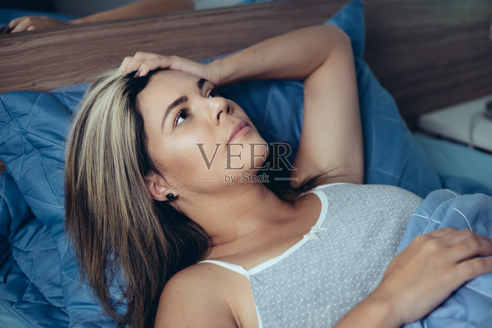 睡眠障碍、失眠。年轻的金发女人醒着躺在床上照片摄影图片
