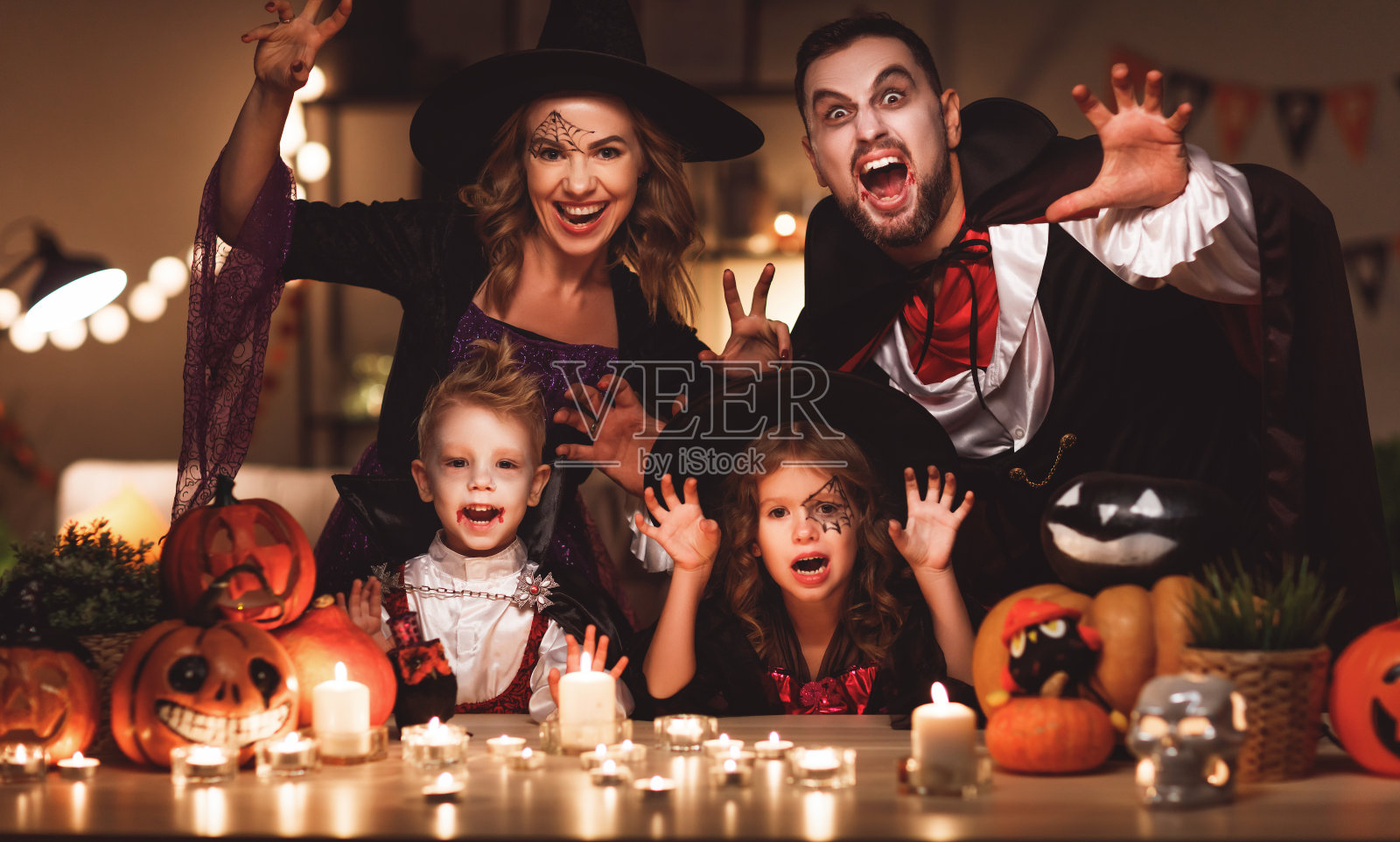 幸福的家庭妈妈爸爸和孩子们在万圣节的服装和化妆在黑暗的家里照片摄影图片
