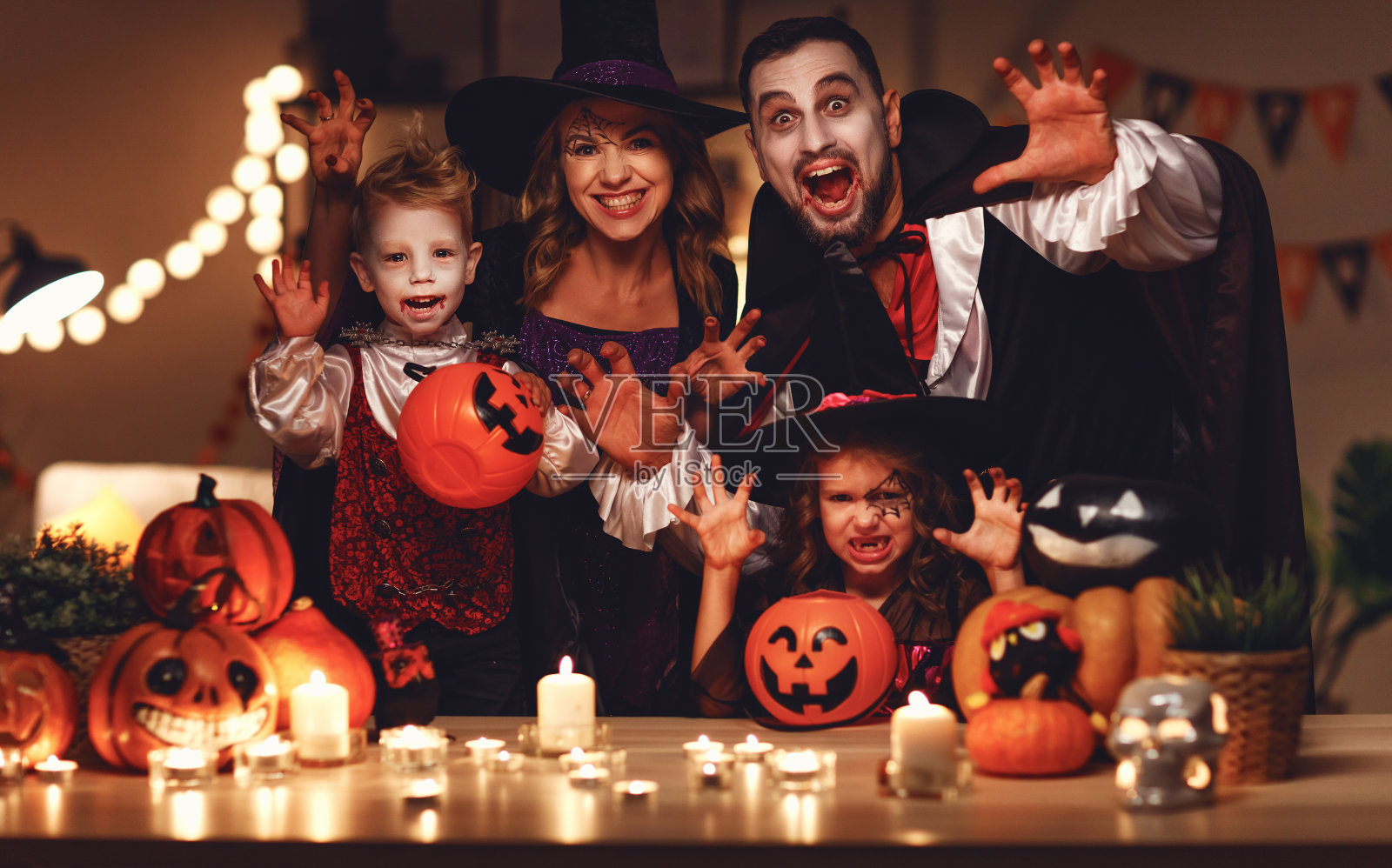 幸福的家庭妈妈爸爸和孩子们在万圣节的服装和化妆在黑暗的家里照片摄影图片
