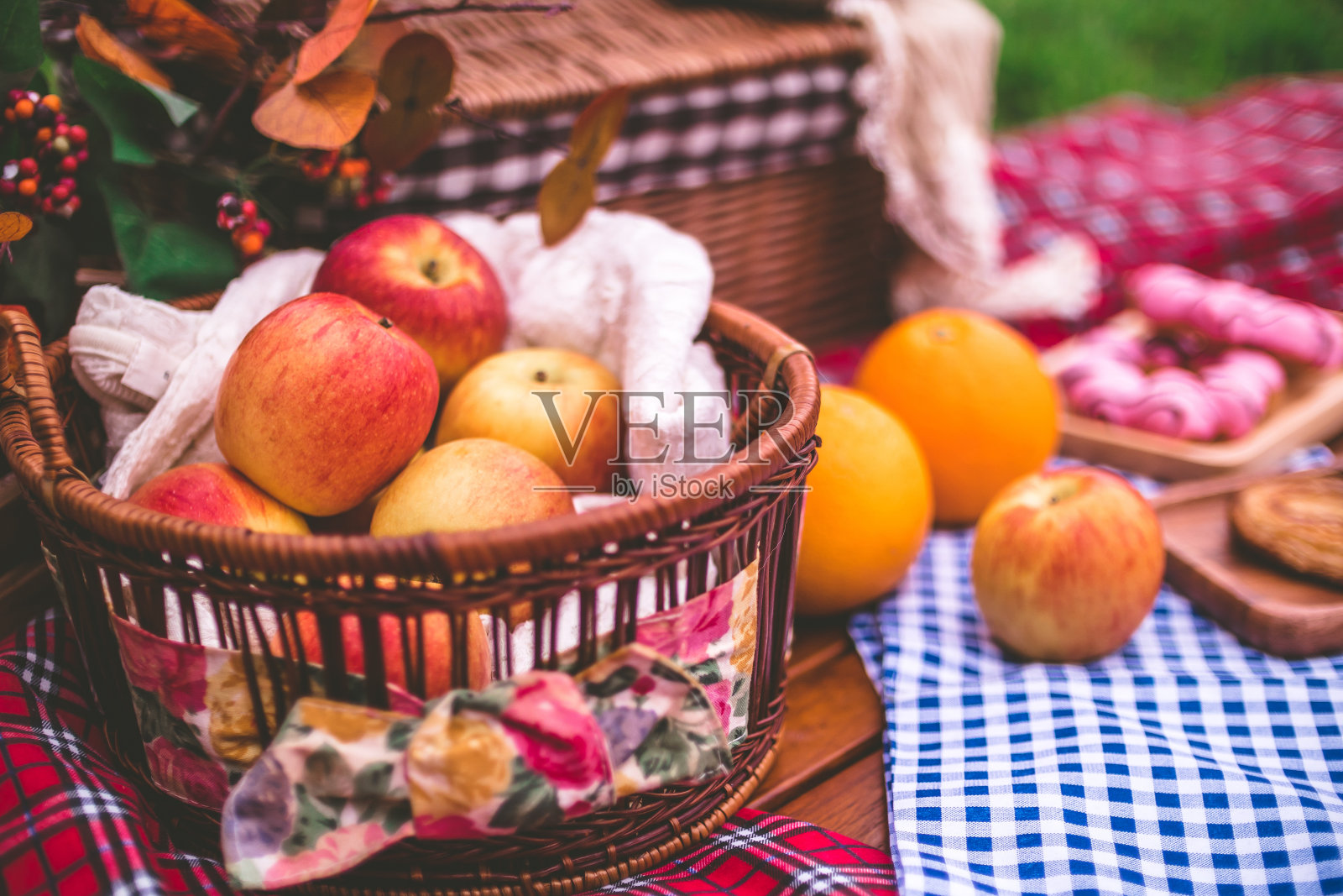 在公园里用毯子包着食物的篮子野餐。照片摄影图片