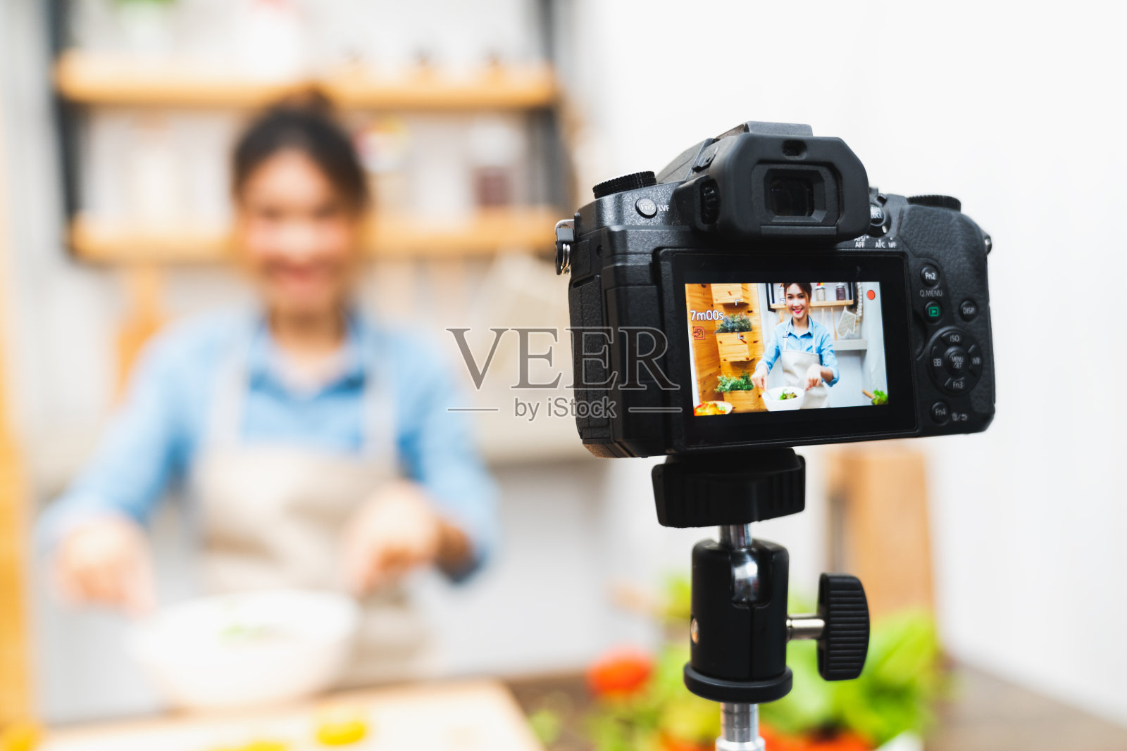 年轻可爱的亚洲博主女孩录制视频教程沙拉烹饪课在家厨房。美食博客，社交媒体爱好广播，或在线学习课程概念照片摄影图片