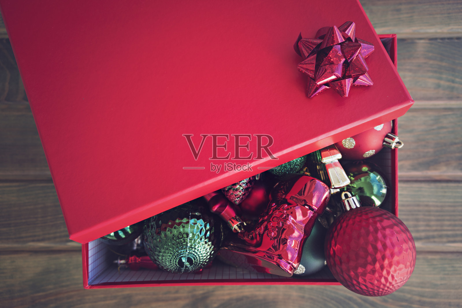 木制背景上装满新年装饰品的红盒子。照片摄影图片