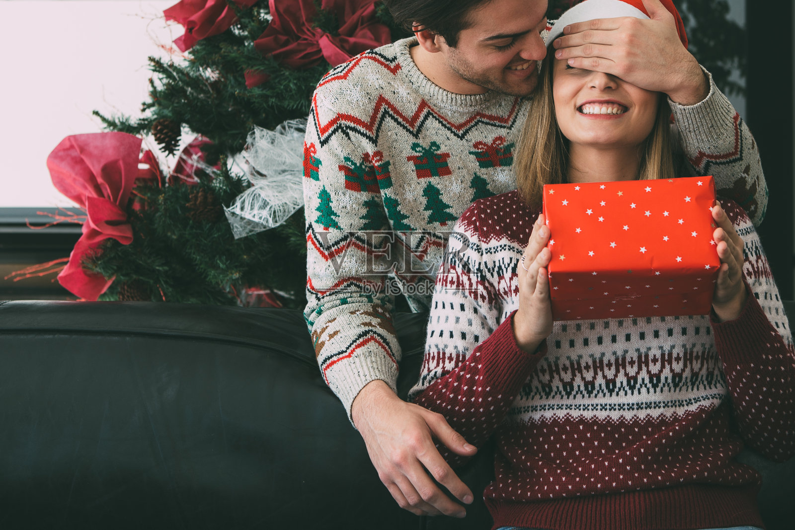 一个年轻人用圣诞礼物给心爱的女人一个惊喜照片摄影图片