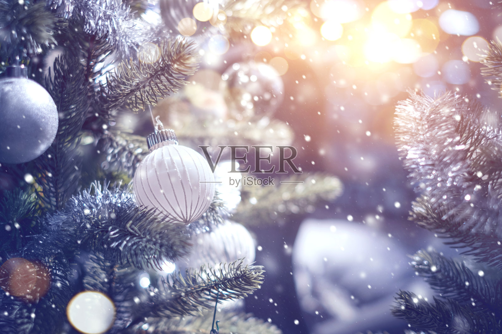 白色和银色的小装饰品挂在装饰好的圣诞树上。照片摄影图片