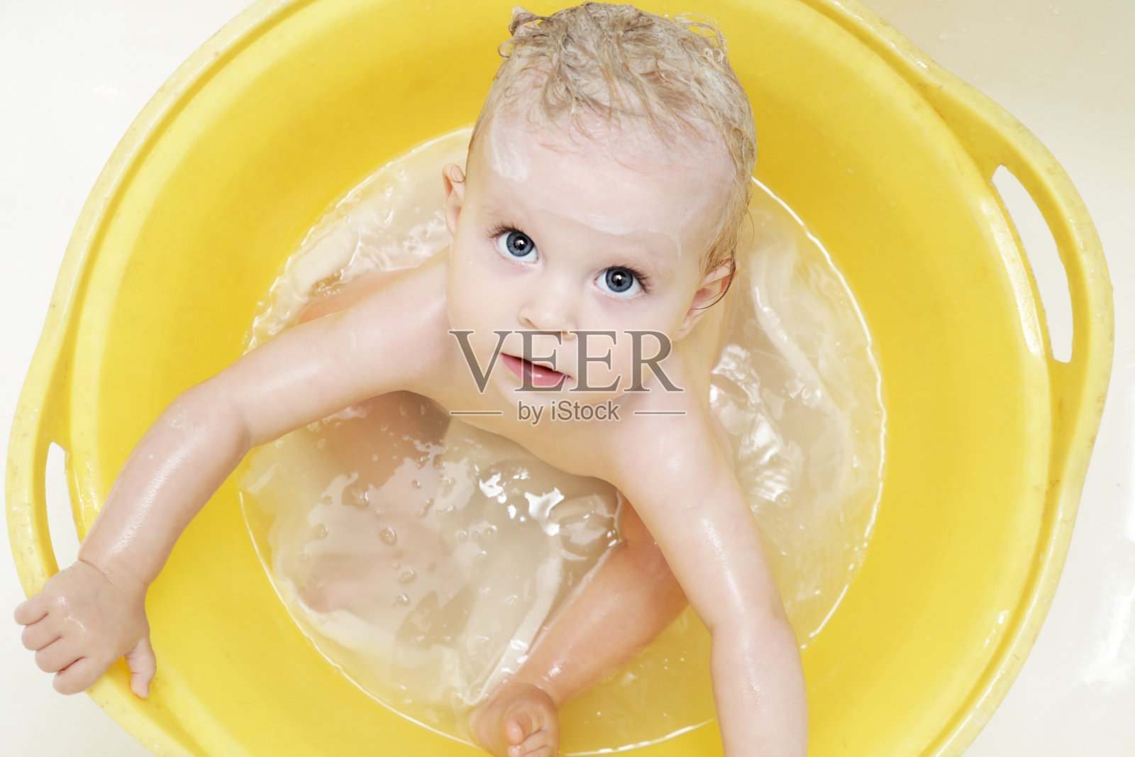 可爱的快乐宝宝在黄色的浴缸里洗澡照片摄影图片