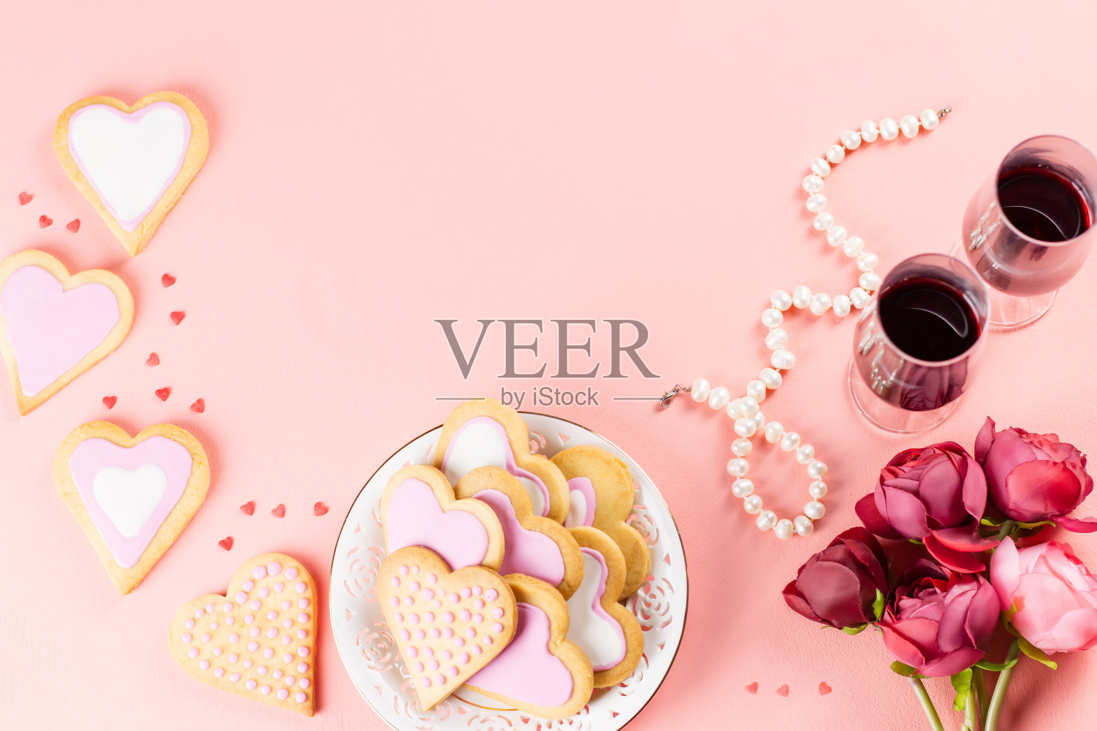 情人节贺卡心形饼干，酒杯和葡萄酒在柔和的粉红色背景。照片摄影图片