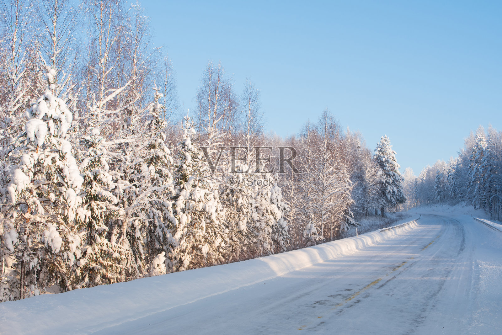 芬兰东部冰雪覆盖的道路蜿蜒穿过冬季的森林景观照片摄影图片