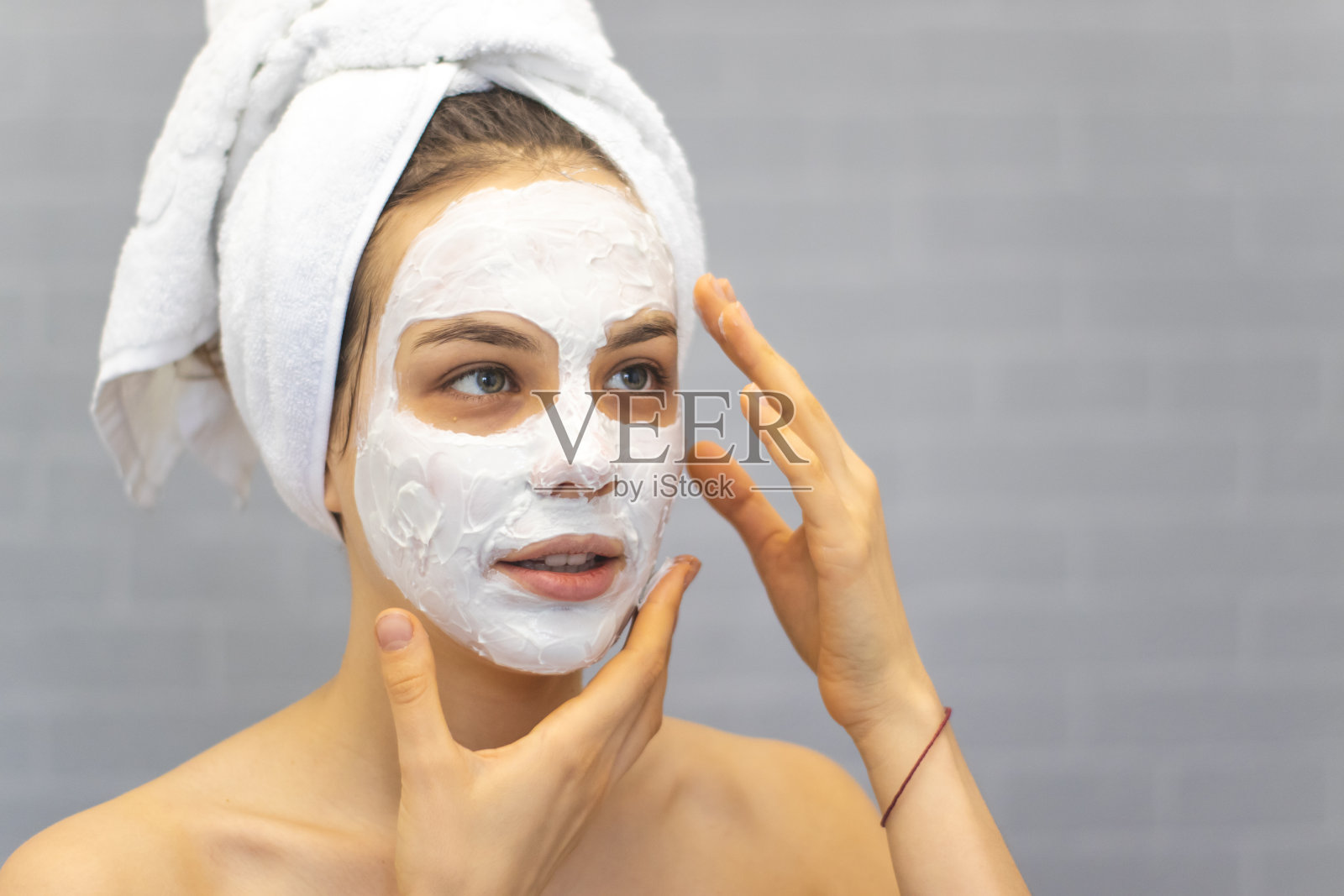 迷人的年轻女子用浴巾和面膜包裹在脸上照片摄影图片